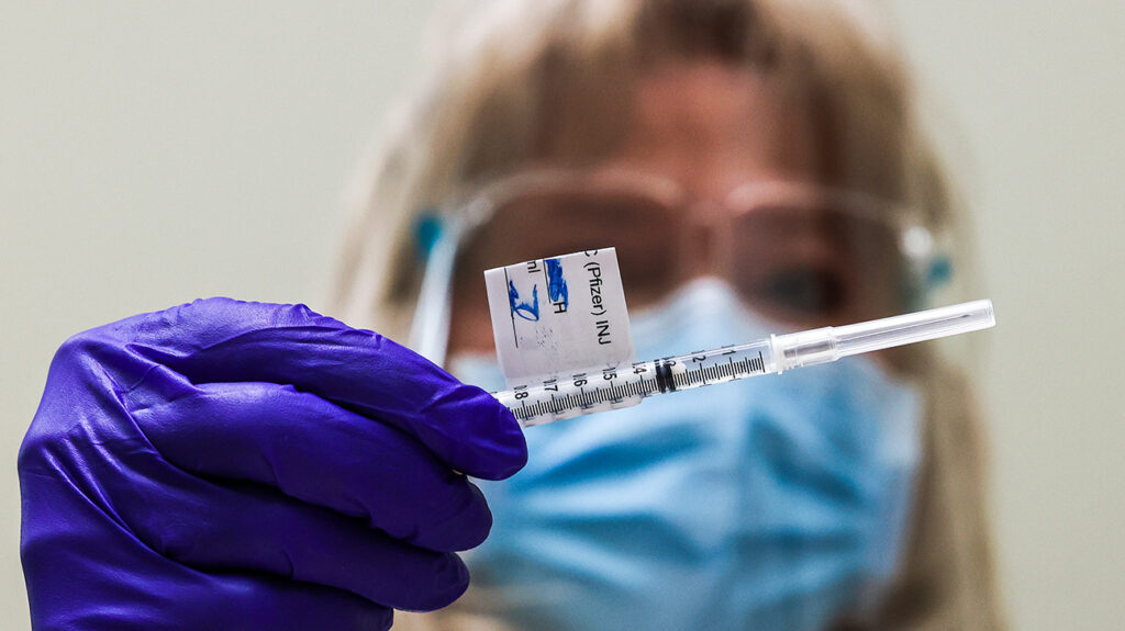 Η εγγεγραμμένη νοσοκόμα του Rocky Mountain Regional VA Medical Center Patricia Stamper εξετάζει μια δόση του εμβολίου Pfizer-BioNTech COVID-19 προτού το χορηγήσει σε έναν επαγγελματία υγείας στο νοσοκομείο στις 16 Δεκεμβρίου 2020 στο Aurora του Κολοράντο. Το Ανατολικό Κολοράντο VA Health Care System επιλέχθηκε ως ένα από τα 37 κέντρα VA σε ολόκληρη τη χώρα για να λάβει αποστολή του εμβολίου λόγω της ικανότητάς τους να αποθηκεύουν το εμβόλιο σε εξαιρετικά κρύες θερμοκρασίες και να εμβολιάζουν μεγάλο αριθμό ατόμων.