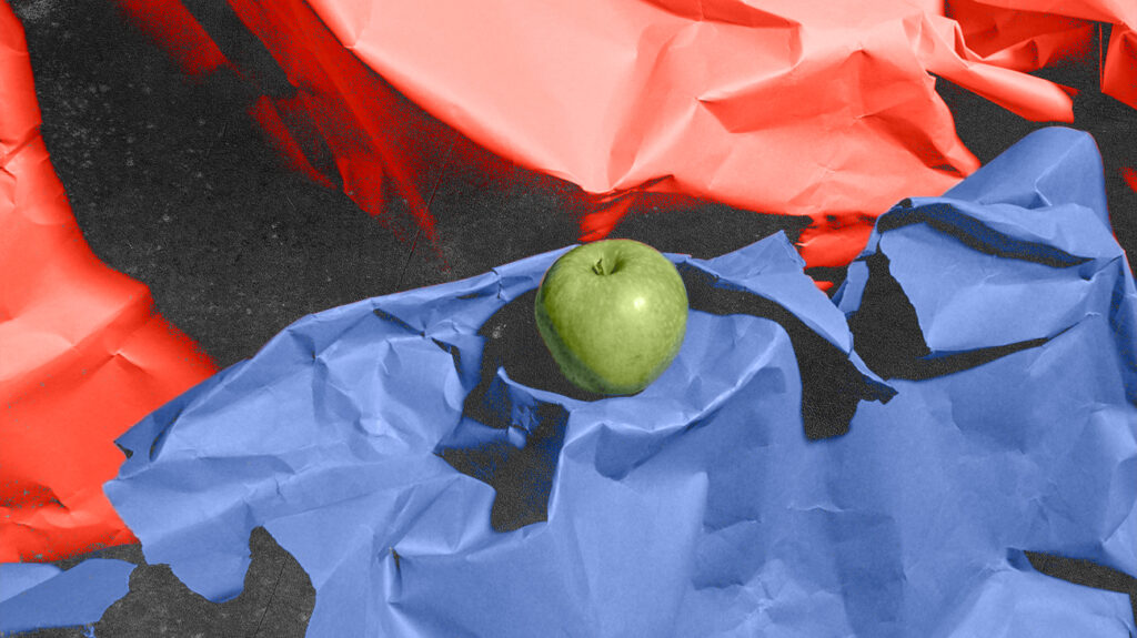 Ein grüner Apfel zwischen zerknittertem rotem und blauem Papier